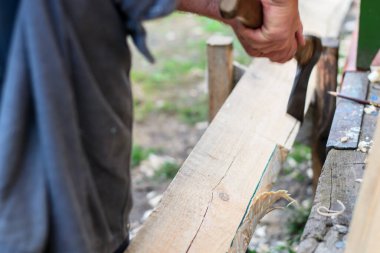 Tahtayı baltayla kesen bir adam.