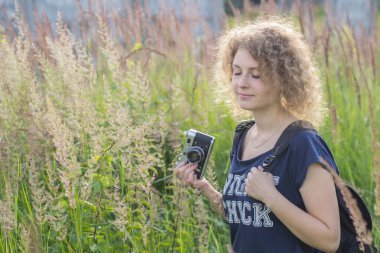 Klasik kameralı kız çimlerin üzerinde duruyor.
