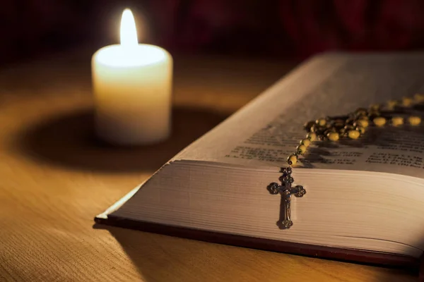 Una Vela Una Biblia Una Cruz Rosario Sobre Una Mesa — Foto de Stock