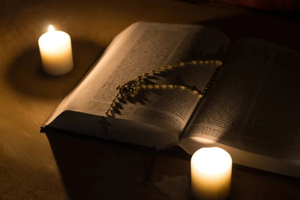 ろうそくと聖書と十字架木のテーブルの上のロザリオ — ストック写真