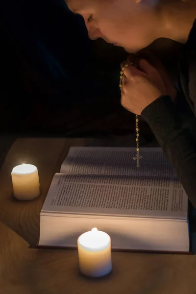 Praying girl over the bible by candlelight