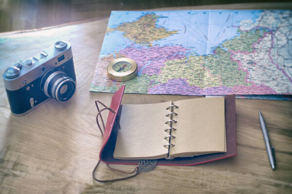 Traveler's things: camera, map, notebook, compass on a wooden background