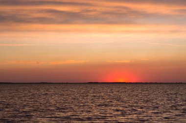 Kızıl günbatımı ve gölde sakin dalgalar