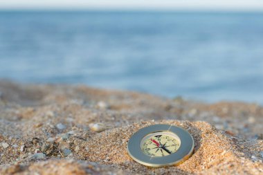 Yönü gösteren bir pusula deniz kabuklarıyla kumların üzerinde yatar.