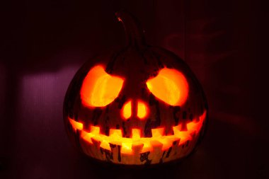 Korkunç cadılar bayramı balkabağı, siyah arka planda bir mumla aydınlatılmış.