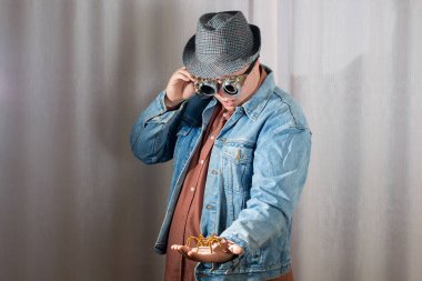 Gözlüklü ve şapkalı bir adam kolunda oturan örümceğe bakıyor, steampunk tarzı.