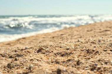 Sahilde kumun yakın çekimi ve arka planda deniz dalgaları, seçici odaklanma