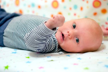 Beşikte sırtüstü yatan şirin bir bebeğin portresi.