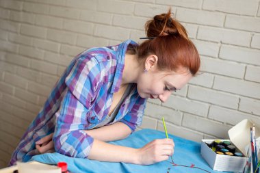Mavi elbiselere akrilik boya çizen bir kızın fotoğrafı.