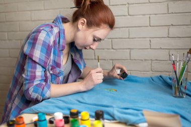 Mavi elbiselere akrilik boya çizen bir kızın fotoğrafı.