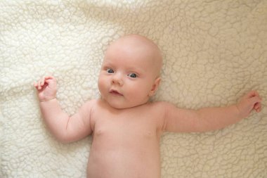 Beyaz bir koyun derisine karşı gülümseyen, yeni doğmuş bir çocuğun portresi.