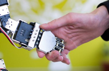 Robot bir eli el sıkışarak tutan bir insan eli fotoğrafı