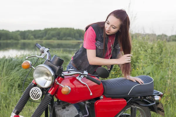 Девушка Стоит Возле Красного Винтажного Мотоцикла Смотрит Зеркало Улице — стоковое фото