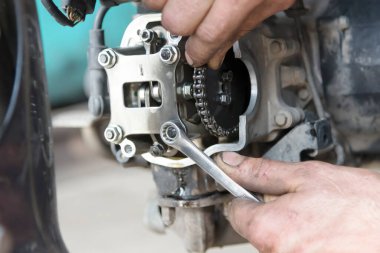 Anahtarı tutan el fotoğrafı, garajdaki motorun tamiri, yakın plan.