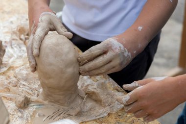 Eller insanın kafasını kilden yapar, yakın plan.