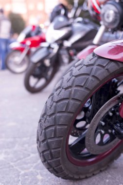 Kırmızı bir motosikletin tekerleği diğer motosikletlerin arka planında büyüktür.