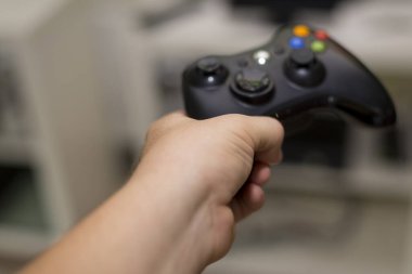 Adamın eli televizyonun önünde oynamak için siyah joystick 'i tutuyor.