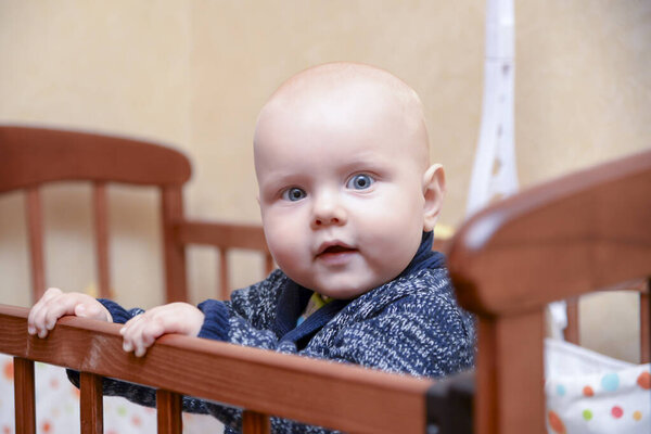 Funny smiling baby boy standing in a crib