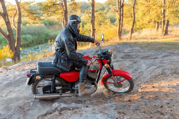森林里骑自行车的人穿着皮夹克头戴安全帽骑着老式复古摩托车 — 图库照片