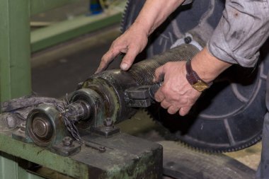 Bir tamirci fabrikada büyük bir makineyi tamir eder..