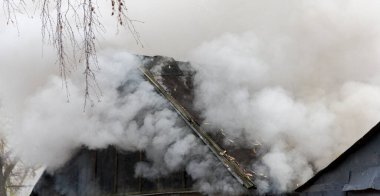 Beyaz kalın duman evin yanan çatısından geliyor.