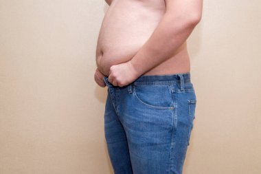 Kot pantolon giyen bir adam, şişman bir göbek, aşırı kilolu olma sorunu.