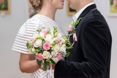 Gelin ve damat bir düğünde bir buket gül tutuyorlar, yakın plan.