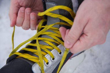 Kışın karda paten bağlayan bir adam, yakın plan.