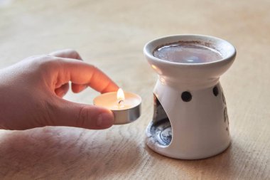 Aroma lambası, gerekli yağ, yanan mum, ahşap arka planda aromaterapi.
