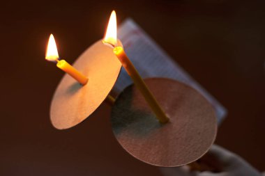 İki ince kilise mumu ve arka planda bir dua sayfası.