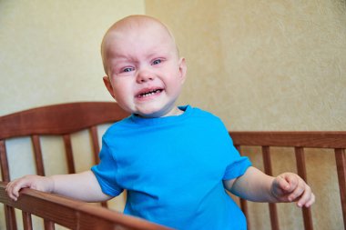 Küçük bir çocuk beşikte duruyor, ağlıyor ve annesini çağırıyor.