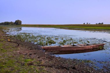 Gün batımından sonra kuruyan nehirde eski ahşap bir tekne..