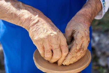 Makinede kil çömlek yapan yaşlı büyükbabanın elleri..