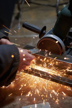 Garajda metal bir parçayı kesen bir adamın elleri, yakın plan..