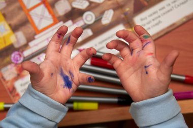 Keçeli kalemle çizim yaptıktan sonra çocuğun kirli elleri, çocuklar için etkinlikler geliştirmek..
