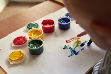 Küçük bir çocuk parmaklarıyla parlak renkler çizer, çocuğun ilk gelişimi..