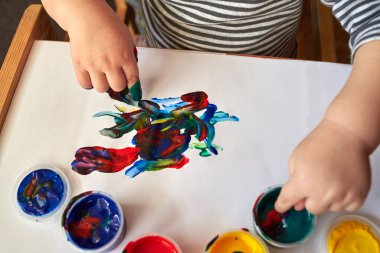 Küçük bir çocuk parmaklarıyla parlak renkler çizer, çocuğun ilk gelişimi..