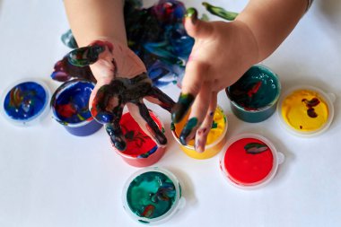Çocuğun ilk gelişimi olan parmak boyalarıyla çizimlerden sonra çocuk kirli ellerini gösteriyor..