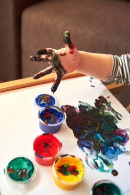 Parlak parmak boyalarıyla resim yapan bir çocuğun elleri, çocuğun ilk gelişimi..