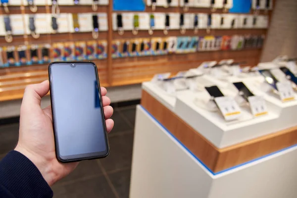 Smartphone in the hand of a man in an electronics store, close-up