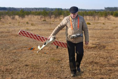 Yaşlı adam kazadan sonra RC uçağını kırık bir pervaneyle tutuyor..