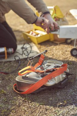Ön planda uzaktan kumandalı bir adam, arka planda odak dışı uçuş için ilkbaharın başında sahada radyo kontrollü bir uçak hazırlıyor..