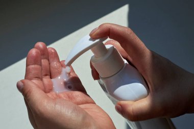 Antibakteriyel sıvı sabun kullanan bir kadının elleri, dezenfeksiyon teması ve enfeksiyonların yayılması ile mücadele.