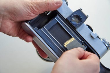 USB flaş belleği film kamerasına yerleştiren el, zaman içinde medyayı değiştirme kavramı..