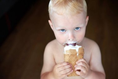 Küçük mavi gözlü, sarışın bir çocuğun portresi dondurma yiyor..