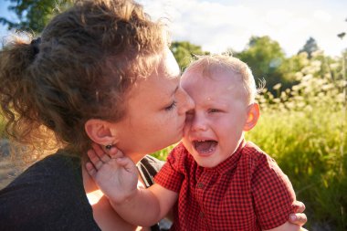 Genç anne iki yaşındaki ağlayan oğluna sarılıyor..