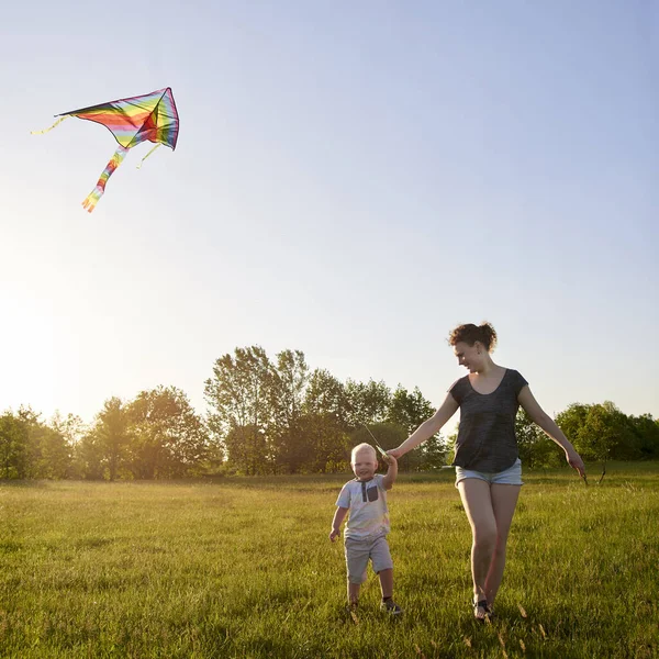 妈妈和她的小儿子在草地上放风筝 主题是夏天的欢乐 — 图库照片