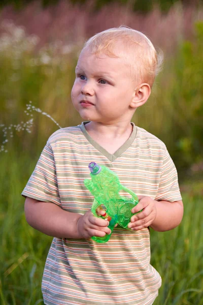 Ein Lustiger Zweijähriger Junge Steht Mit Einer Wasserpistole Auf Einer — Stockfoto