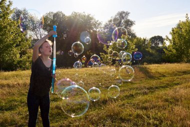 Yazın çayırda sabun köpüğü üfleyen bir kadın, yaz eğlencesi, yaz zamanı.