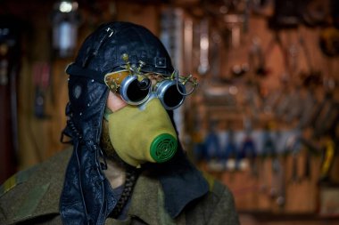 Solunum cihazına bağlı sakallı bir adam ve steampunk tarzında gözlükler, palto giymiş, post tapokalipsis konsepti.